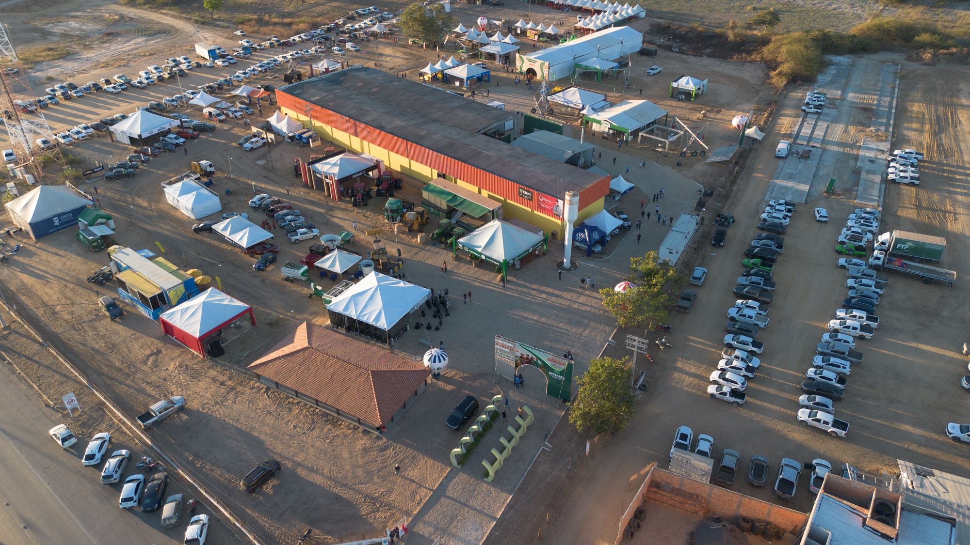 Vista aérea do pavilhão e das tendas da feira com tratores e implementos expostos ao redor