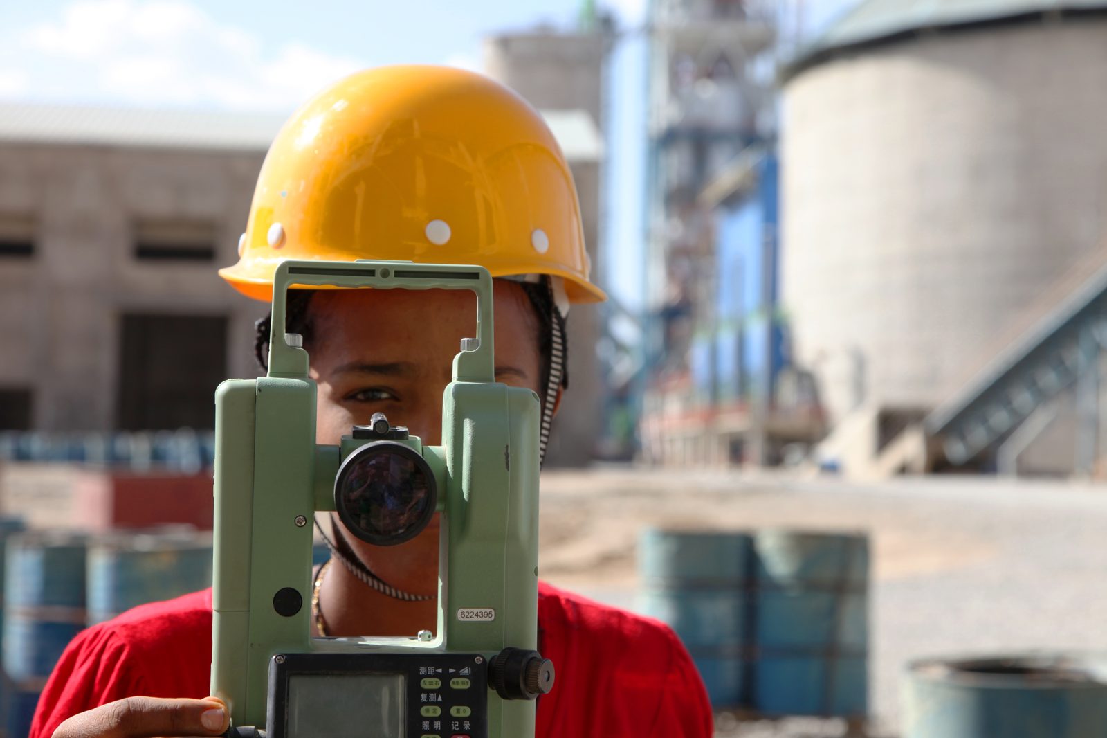 Técnico realizando medição topográfica com teodolito em obra industrial